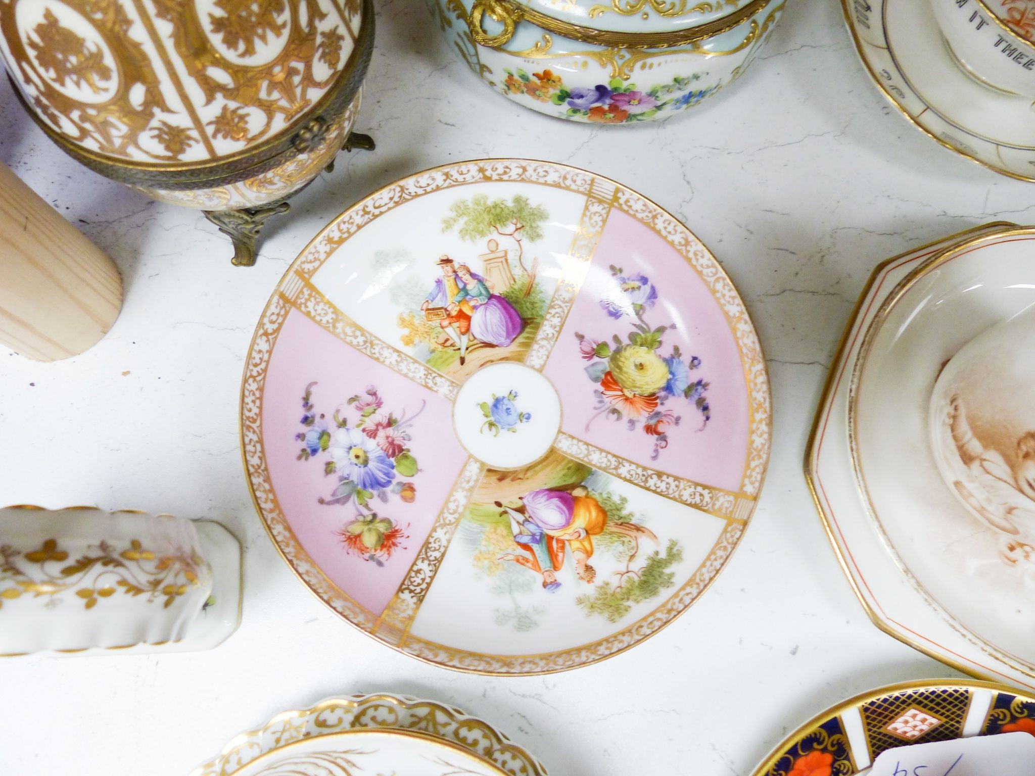 A group of Dresden and Continental porcelain cups and saucers boxes and covers and a scent bottle, 14 cm high